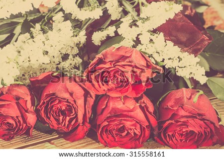 Red roses flowers on wood background useful as greeting card, vintage photo.