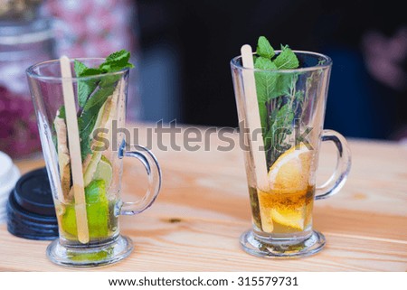 Beautiful green black tea drink with lemon, cinnamon, mint, thyme and ginger, beautiful coloured alcohol cocktail on corporate party event, catering, near bar, on a banquet, buffet