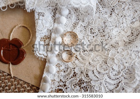 Two gold rings on dress of the bride.