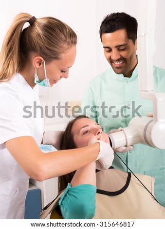 Cheerful dentist doing digital xray in dentist office