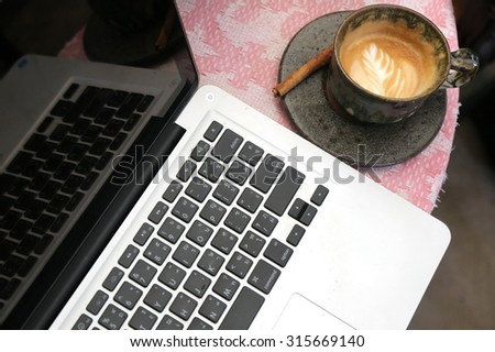  laptop on table with coffee cup in coffee shop, businessman hand busy at office desk,hardworking life ,Layout of comfortable working space on wooden, internet laptop phone laying on it