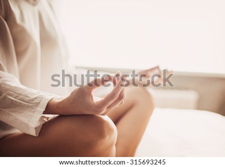 Young woman meditating in the lotus pose at home. Fit girl doing exercises, practicing yoga indoors. Harmony, yoga practice, balance, meditation, relaxation at home, healthy lifestyle, mindfulness Royalty-Free Stock Photo #315693245