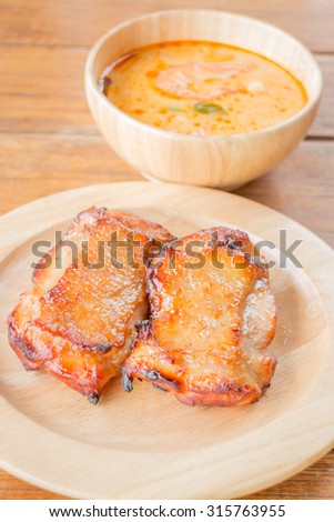 Chicken steak and spicy soup on wooden table, stock photo