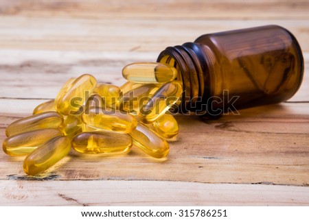 fish oil capsules and container with wooden background