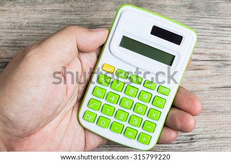 Man hand hold Calculator on Wood Background