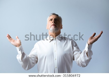 Portrait of concentrated old man praying to God and looking up