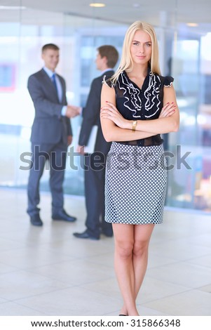 Portrait of a beautiful office worker standing in an office with colleagues in the background