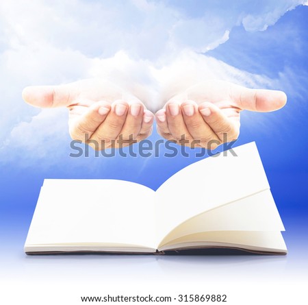 Blank opened book, diary, photo album over human open empty hand with palms up over amazing blue sky background.