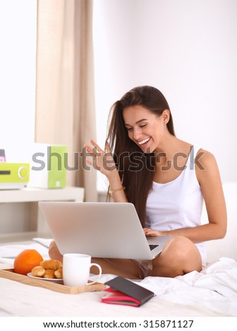 Young beautiful woman sitting in bed talking on the phone