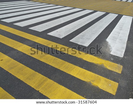 lots of stripes on the asphalt indicating a crossing of pedestrians