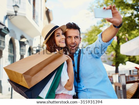 Happy couple taking selfie after shopping in the city