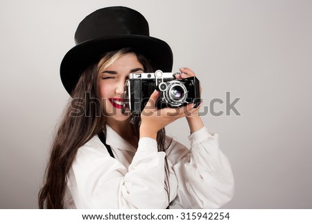 Woman in hat taking photograph from vintage film camera