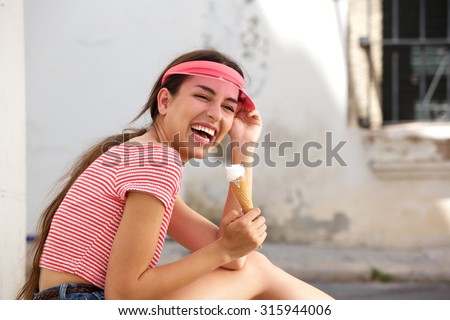 Side portrait of a young woman laughing outside with ice cream cone