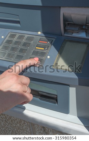 Woman using cash machine in building wall with screen