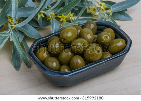 Green olives in the bowl with leaves
