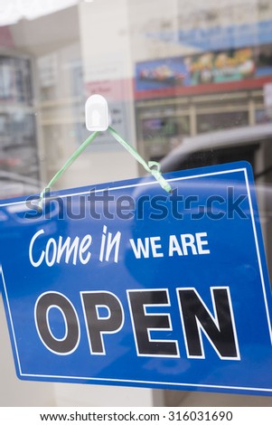 Come in we are open sign hanging on a window door outside an office or a shop