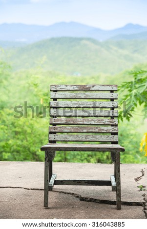 Old wooden chair on broken cement floor on green mountains range background