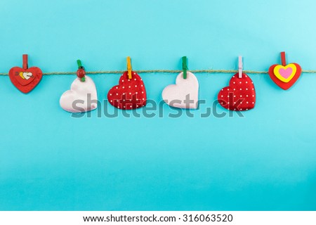 Hanging little cotton heart on blue background with copy space. Love concept on Valentine day
