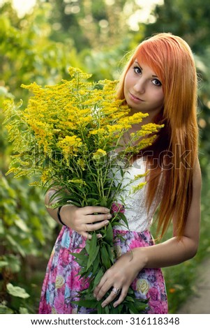 Beautiful young ginger girl hold a bunch of yellow flowers. Color effects and a custom white balance are used on this picture.