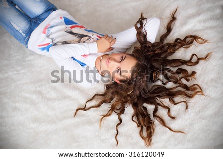 Portrait of a pretty teen girl lying on the floor with her long hair wavy