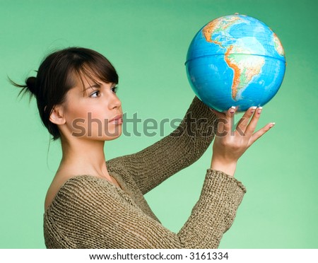 The girl holds on a shoulder the globe on a green background