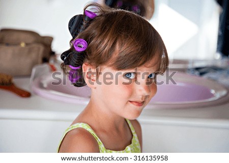 Portrait of girl in the bathroom with hair curlers