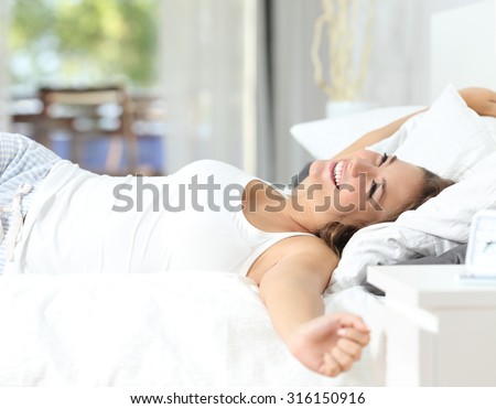 Happy girl waking up stretching arms on the bed in the morning Royalty-Free Stock Photo #316150916