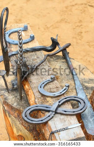 Handicrafts knives, horseshoes on wooden stump at outdoor fair