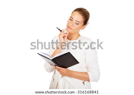 Young businesswoman thinks about some idea and makes a notes.