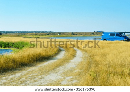 Field road and car on a background sky