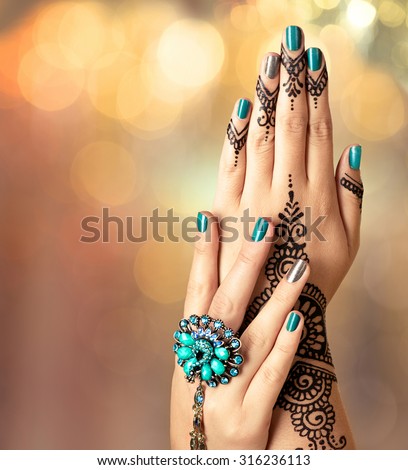 Woman Hands with black mehndi tattoo. Hands of Indian bride girl with black henna tattoos. Hand with perfect turquoise manicure and national Indian jewels. Fashion. India. Marriage traditions Royalty-Free Stock Photo #316236113