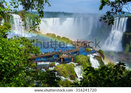 Tourists at Iguazu Falls, one of the world's great natural wonders, on the border of Brazil and Argentina. Royalty-Free Stock Photo #316241720