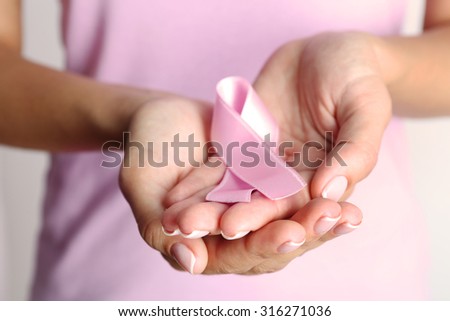Pink ribbon in woman's hands close up Royalty-Free Stock Photo #316271036