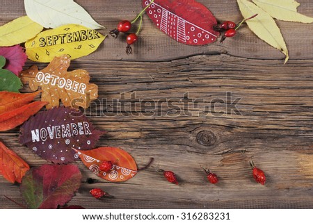 close-up of three months of autumn leaves painted on a wooden board on a background of the studio