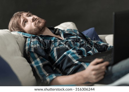 Bored man with a laptop on the couch