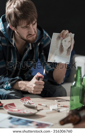 Angry man burning a photo of his ex girlfriend