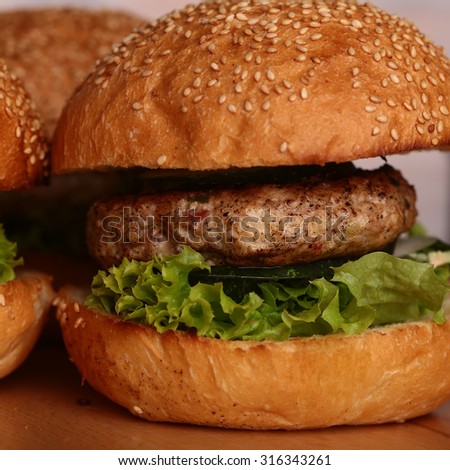Few big delicious appetizing fresh burgers of green lettuce leaf cheese meat cutlet and white bread bun with sesame seeds closeup, square picture