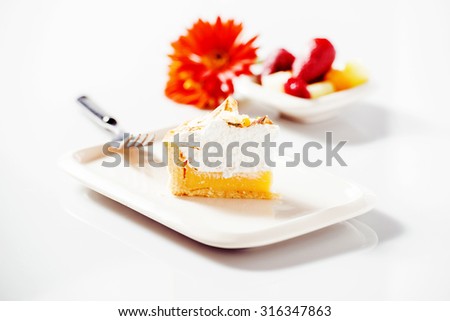 Lemon meringue pie with a flower and plate in the background