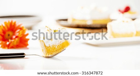 Lemon meringue pie with a flower and plate in the background