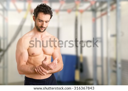 Male with pain in his wrist, isolated in a gym