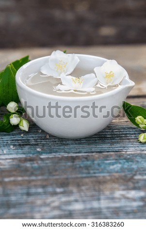 Spa and wellness setting with sea salt, oil essence, jasmin flowers and towels on wooden background.  Relax and treatment therapy. space for text.  Selective focus. Close up.
