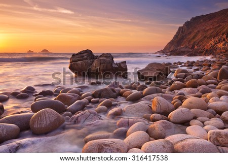 The beautiful rocky beach of Porth Nanven in Cornwall, England at sunset.