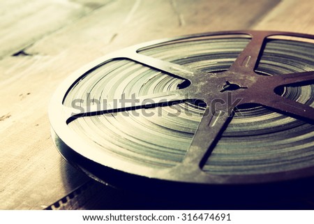 image of old 8 mm movie reel over wooden background. retro style image 