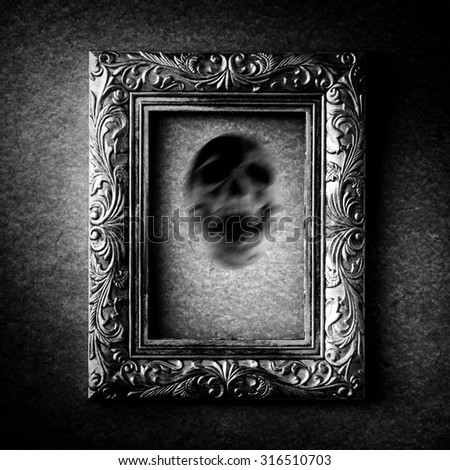 Silver vintage photo frame with soul of skull over grunge background, black and white, halloween concept