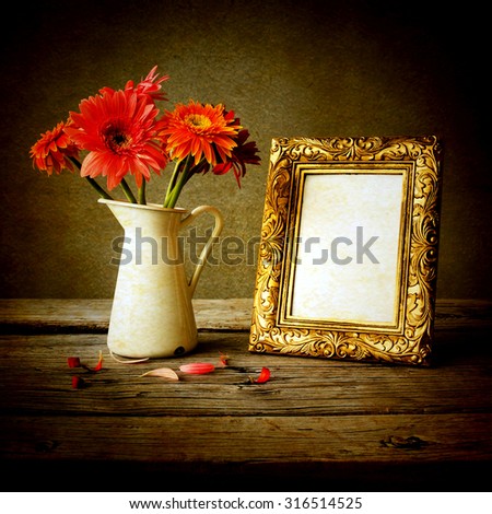 Gold vintage photo frame and flowers on wooden table over grunge background