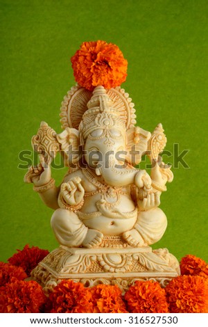 Hindu God Ganesha. Ganesha Idol on Green Background with flowers.
