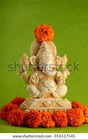 Hindu God Ganesha. Ganesha Idol on Green Background with flowers.
