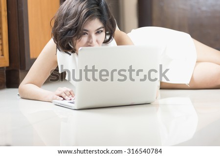 happy asia woman lying on floor with the laptop at home