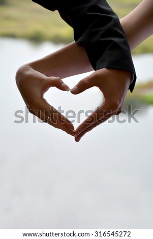 Silhouette of two hands of the bride and groom in a heart shape