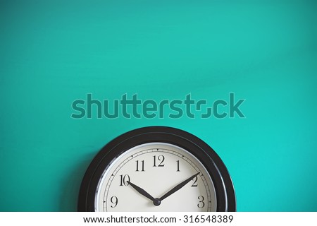 Clock on mint green wall background. Vintage effect. Concept of Time. Royalty-Free Stock Photo #316548389